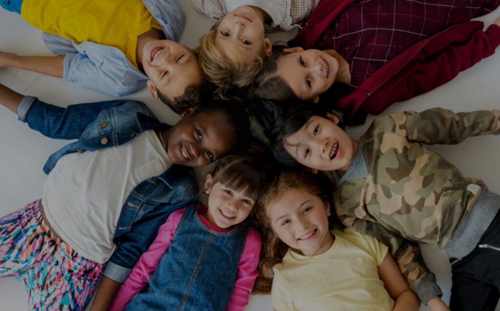 A group of happy kids smiling and laying down in a circle