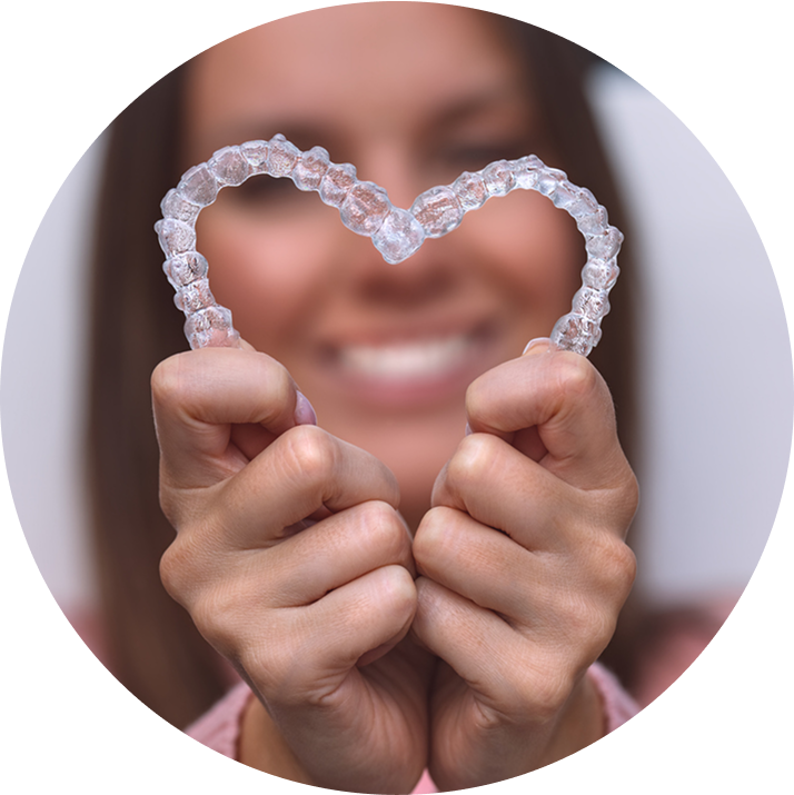 Close Up Of Smiling Woman Making Heart Shape Out Of Clear Aligners