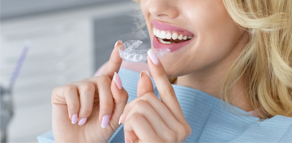 Close Up Of Smiling Young Woman Inserting Clear Aligner