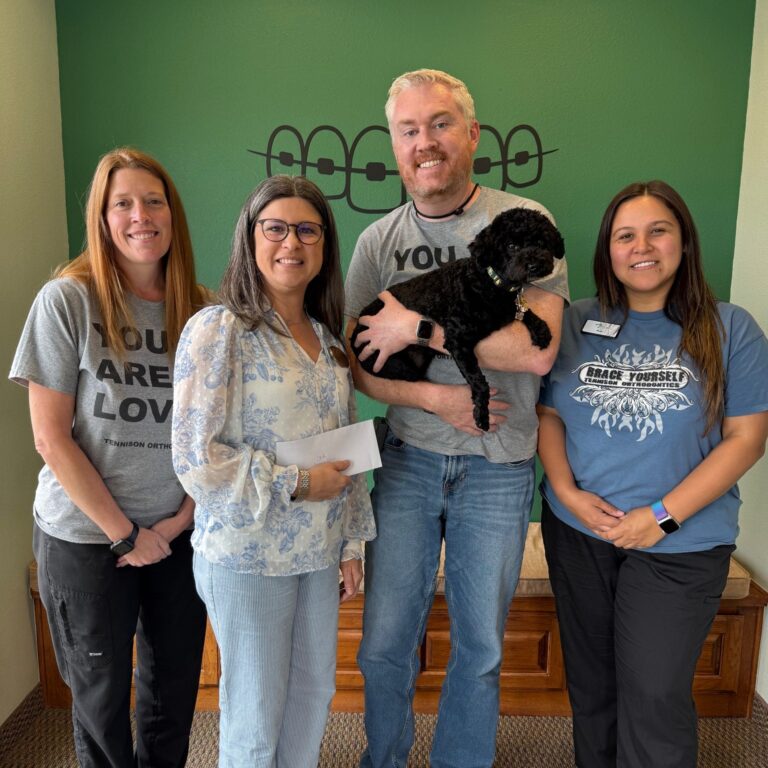 Orthodontist Dr. Tennison holding a dog and posing with members of CASA of Johnson County