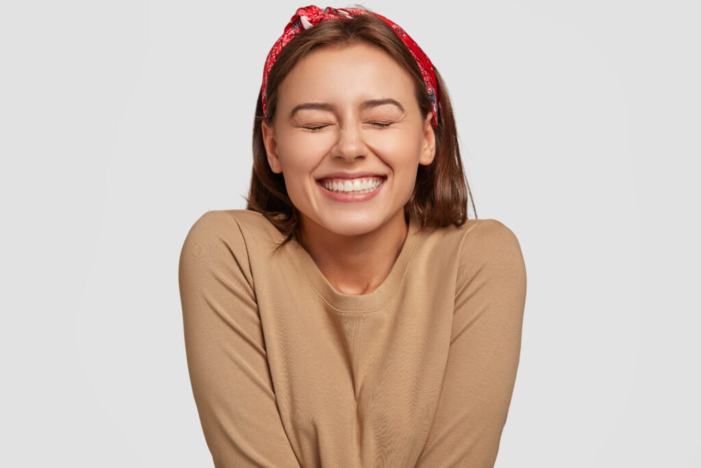 Young woman with a red bandana and an aligned smile smiling in relief and excitement