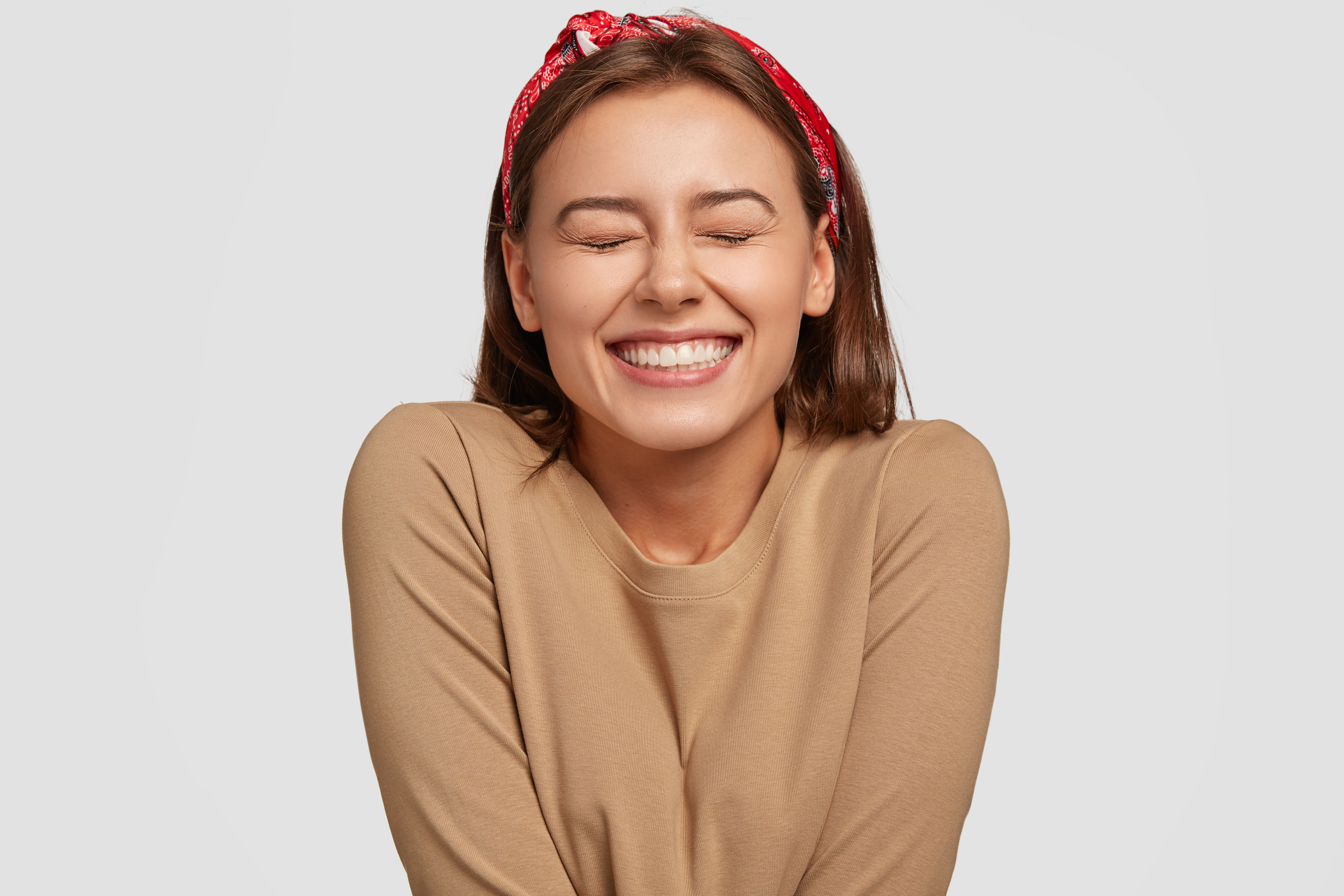 Young woman with a red bandana and an aligned smile smiling in relief and excitement